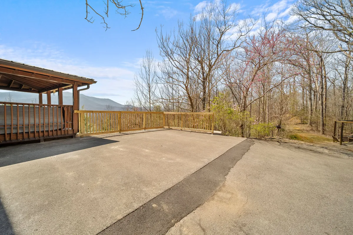 A peaceful wooden deck overlooking expansive mountain views with bare trees, showcasing the tranquility and privacy of the outdoor setting. The open space is perfect for morning coffees, evening conversations, or simply soaking in the panoramic vistas.