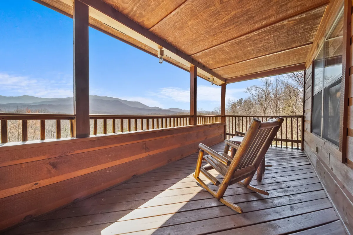 A tranquil porch scene with a rocking chair, wooden railing, and an expansive mountain view. The setting is ideal for relaxing, reflecting, or enjoying quiet moments together after a day of adventure.
